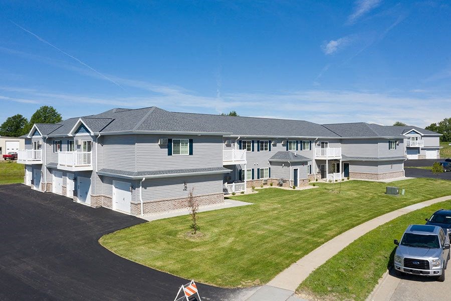 a large white house with a yard and cars parked in a driveway