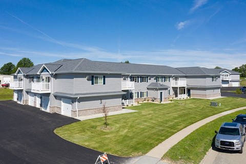 a large white house with a yard and cars parked in a driveway