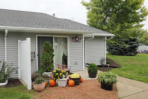 a house with flowers and pumpkins in front of it