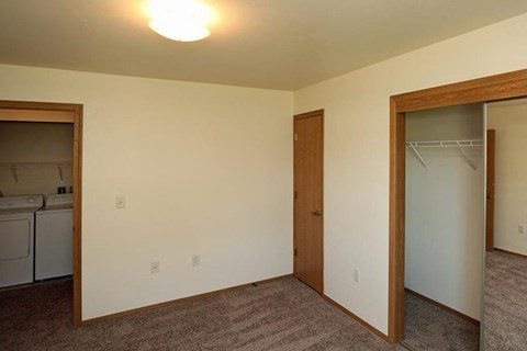 an empty room with a closet and a door to a kitchen