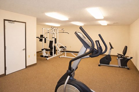 A gym with a variety of equipment including treadmills, weights, and exercise machines.