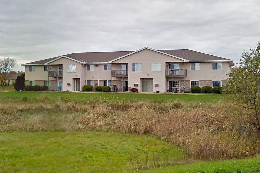 a large apartment building in front of a green field