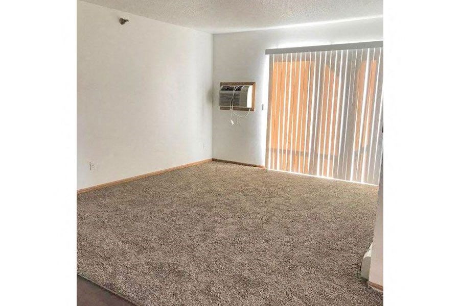 an empty living room with a window and a television