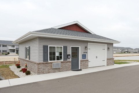 a small gray building with a white door and a sidewalk