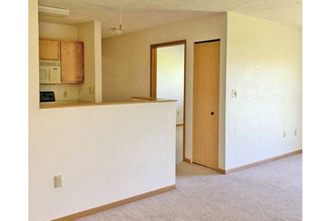 an empty living room with an open door to a kitchen
