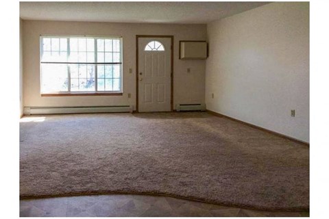 an empty living room with a window and a door