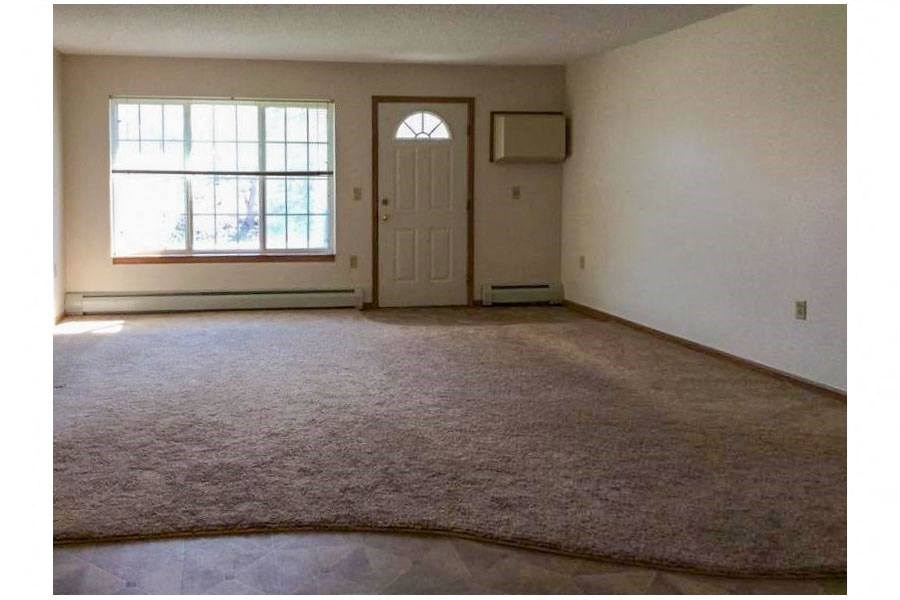 an empty living room with a window and a door