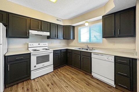 A kitchen with black cabinets and white appliances.
