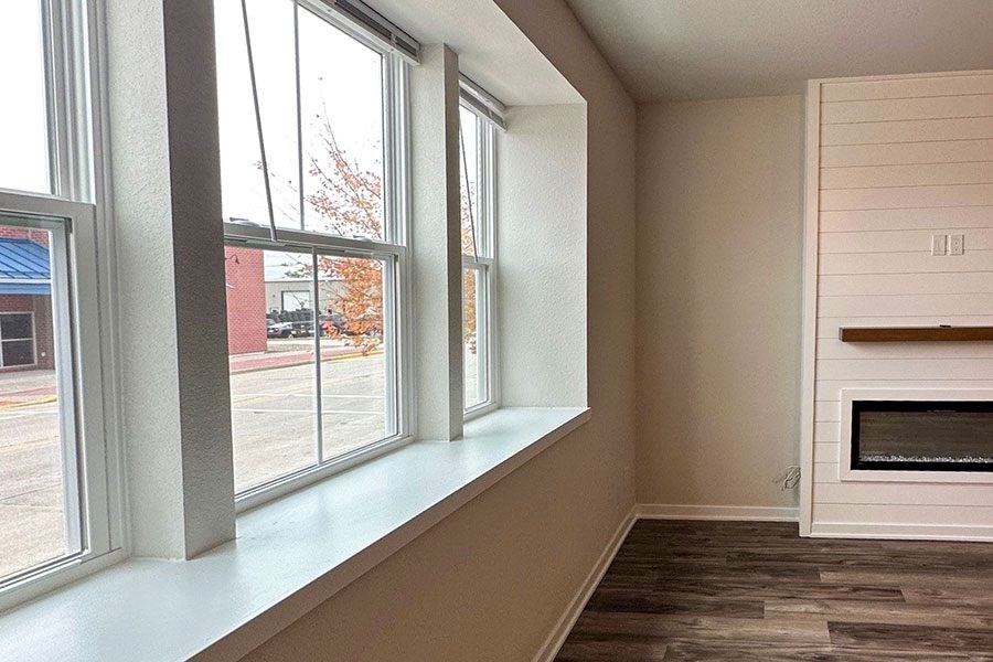 A room with a fireplace and a window overlooking a parking lot.