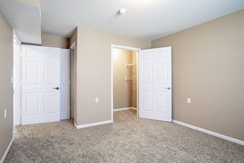 an empty bedroom with two doors and a closet