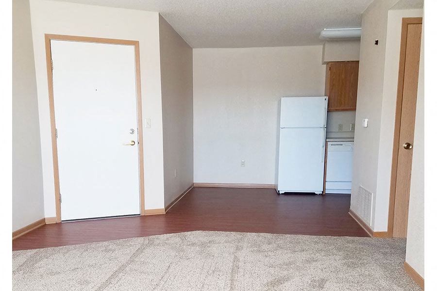 A white refrigerator in a room with a brown carpet.