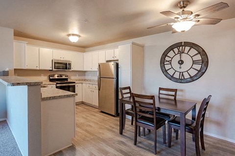 A kitchen with a table and chairs and a clock on the wall.