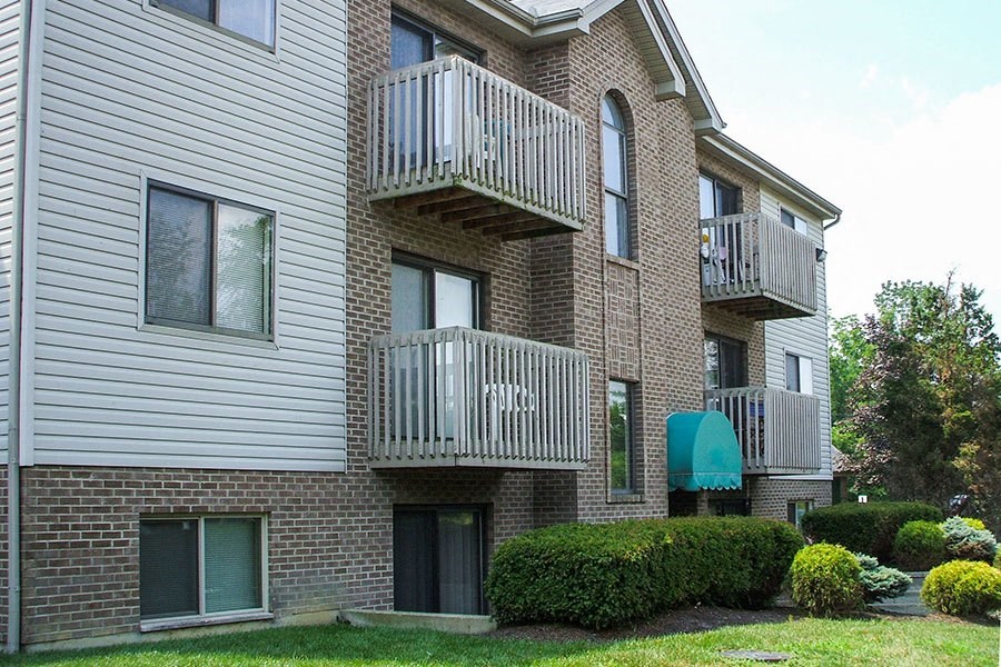 A multi-story apartment building with balconies and a green awning.
