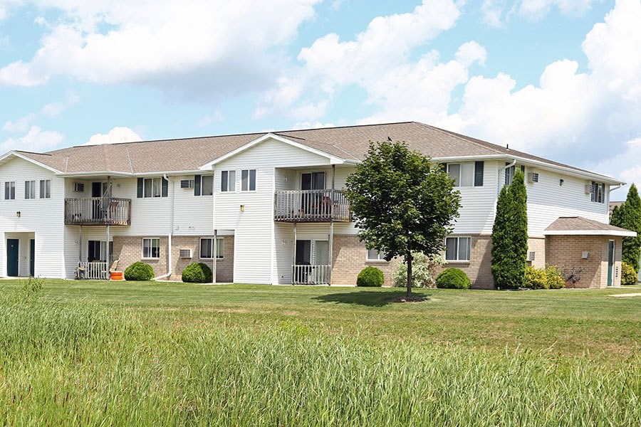 A white apartment building with a green lawn in front.