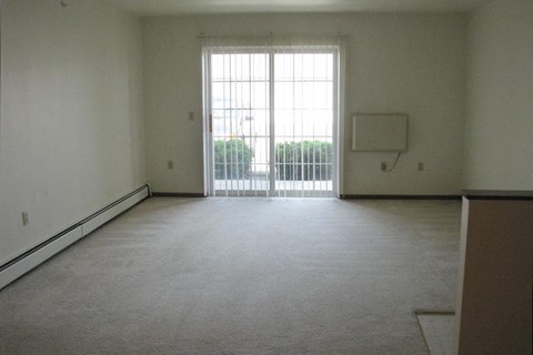 A room with a carpeted floor and a sliding glass door.
