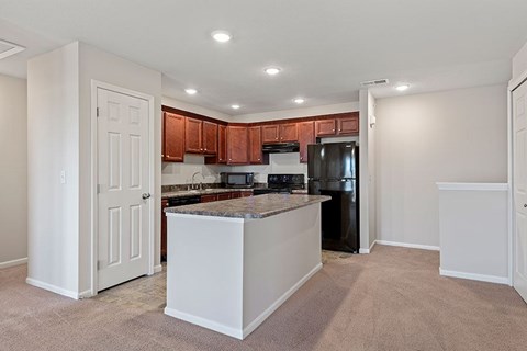 A kitchen with white cabinets and a black refrigerator.