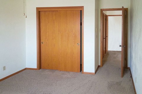 an empty room with a wooden door and a hallway