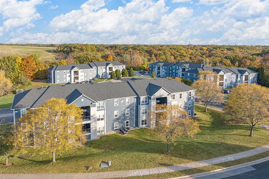 an aerial view of an apartment building with trees and a grass field