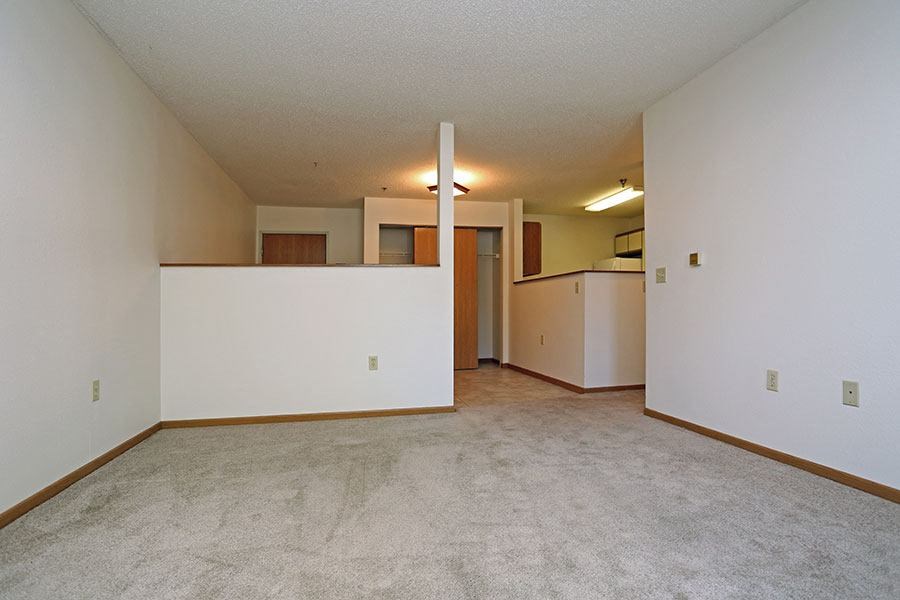 an empty living room and kitchen with white walls