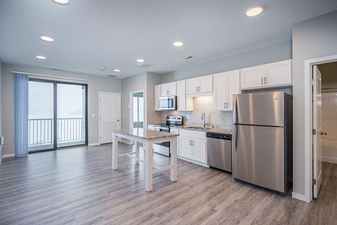 A modern kitchen with stainless steel appliances and a dining table.