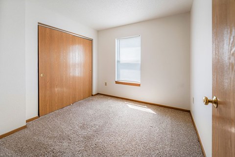 A room with a carpeted floor, a door, and a window.