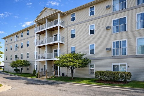 Apartment building with balconies and trees in front.