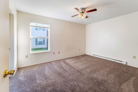 A room with a ceiling fan and carpeted floor.