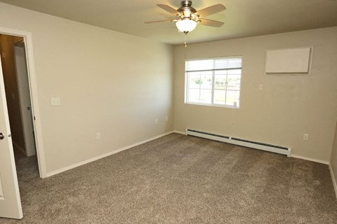 an empty room with a ceiling fan and a window
