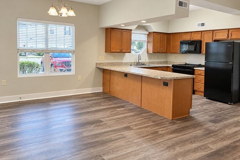 A kitchen with wooden cabinets and a black refrigerator.
