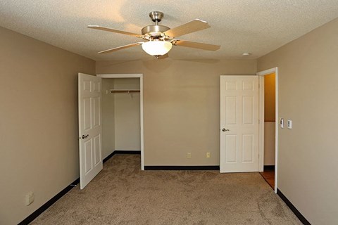 A room with a ceiling fan and carpeted floor.