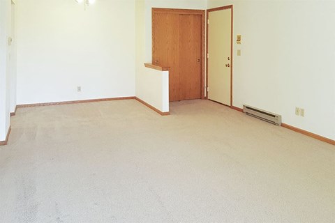 an empty living room with a door to a bedroom