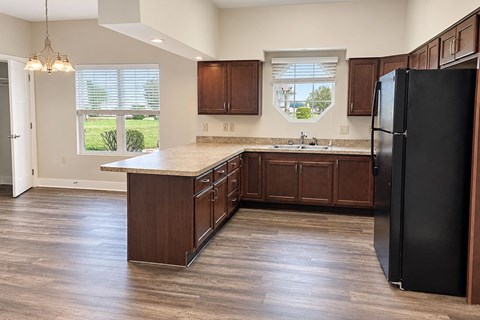 A kitchen with wooden cabinets and a black refrigerator.