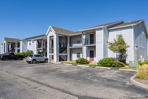 A car is parked in front of a building with a white car parked in front of it.