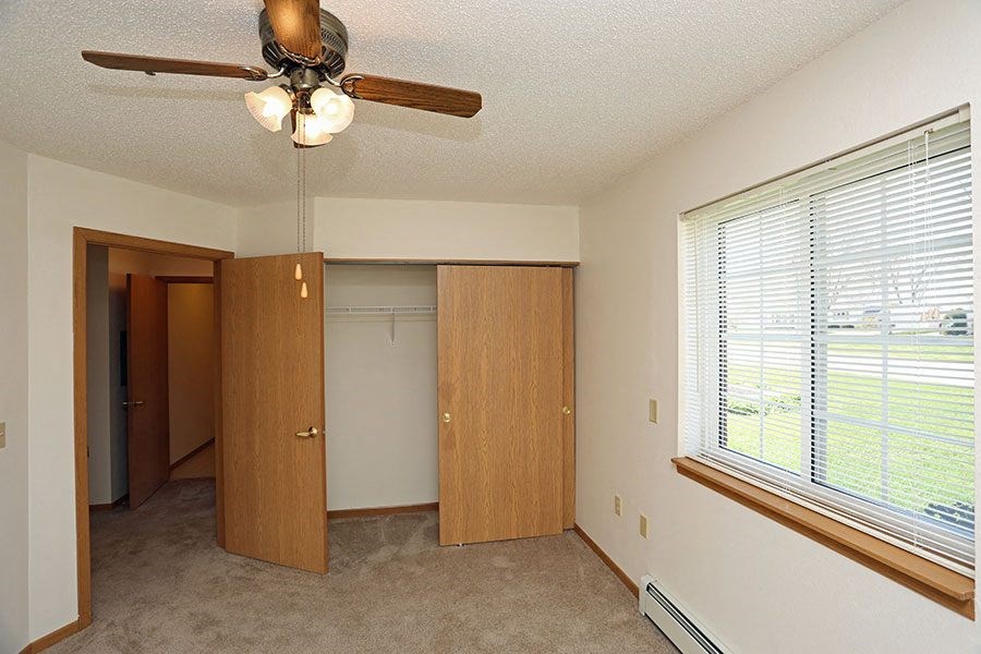 a bedroom with a ceiling fan and a closet