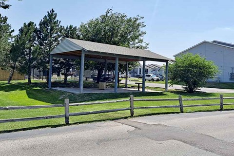 A pavement with a wooden fence and a pavilion in the background.