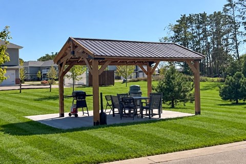 A wooden pergola with a metal roof and a table and chairs underneath it.