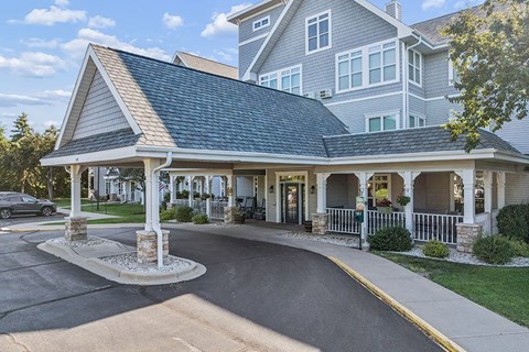 A large house with a covered porch and a car parked in front.