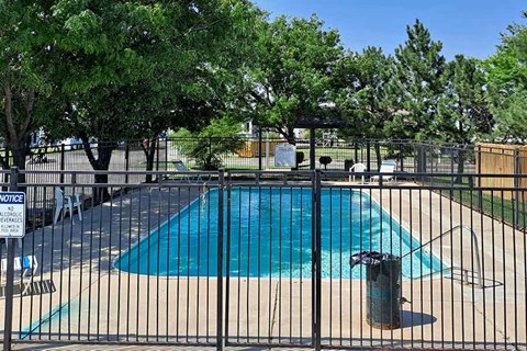 A pool surrounded by a black fence with a sign on it.