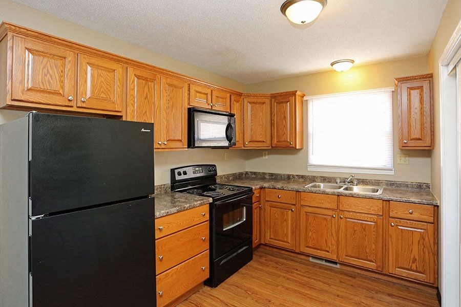 A kitchen with wooden cabinets and a black refrigerator.