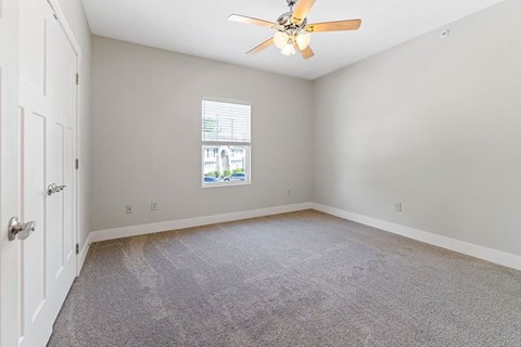 A room with a ceiling fan and carpeted floor.