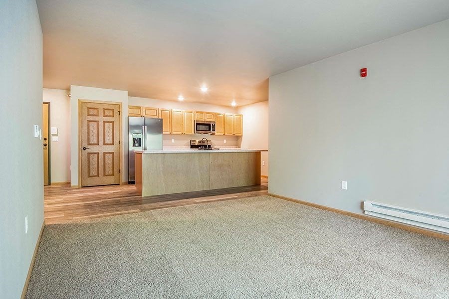 an empty living room and kitchen with a refrigerator