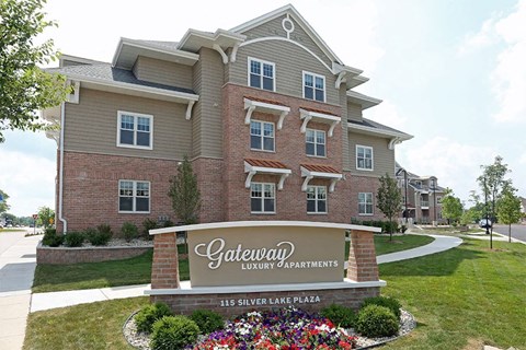 A sign for Gateway Luxury Apartments is in front of a building.