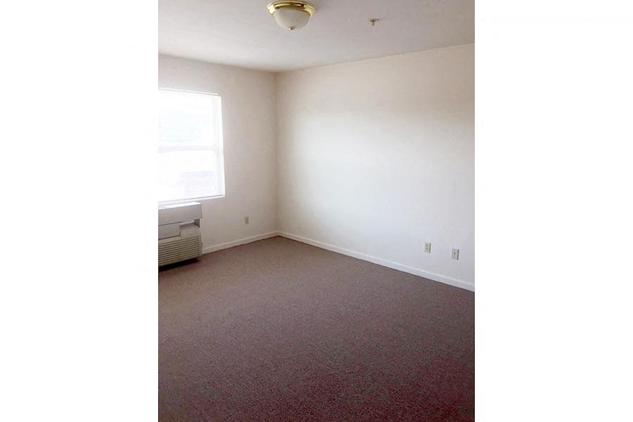 an empty room with a window and a red carpet