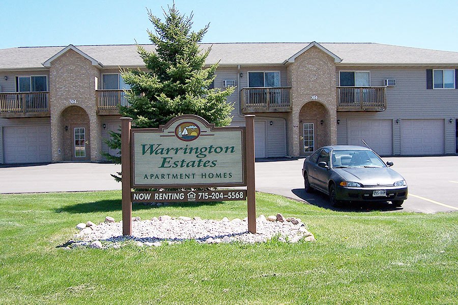 a sign in front of a building with a car parked