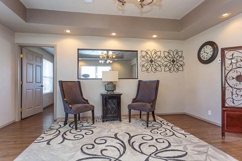 a living room with two chairs and a clock on the wall