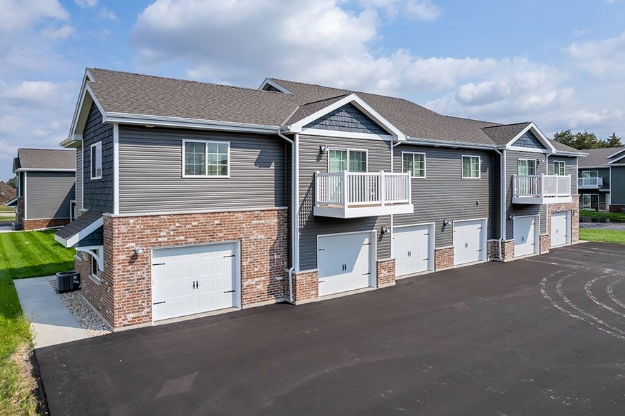 A large grey house with a garage door and a balcony.