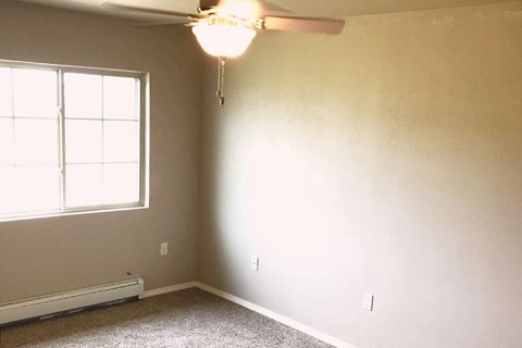 an empty room with a ceiling fan and a window
