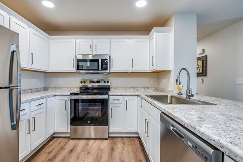 A kitchen with white cabinets and a granite countertop.