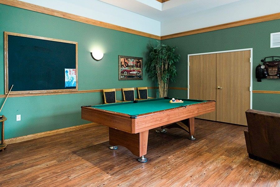 A pool table in a room with green walls.