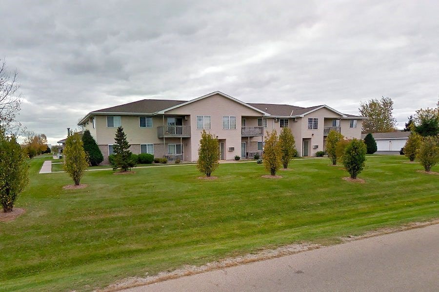 an apartment building on the side of a grass field